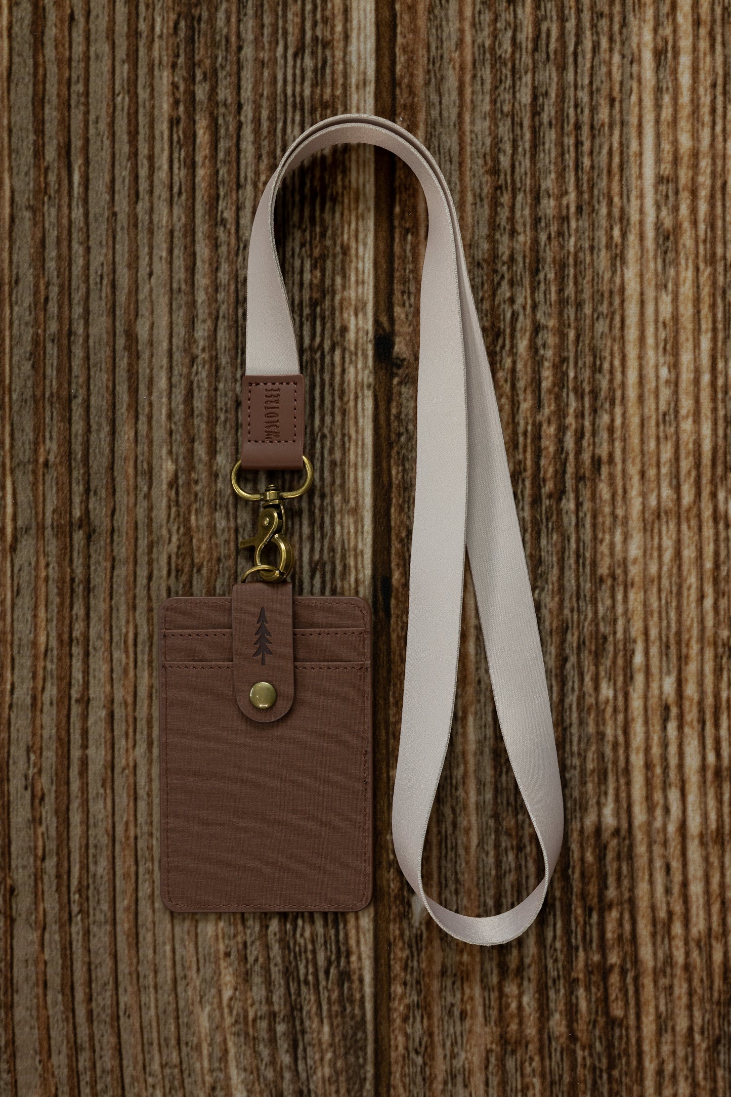 Tan Neck Lanyard attached to a brown vegan leather cardholder embossed with a pine tree design