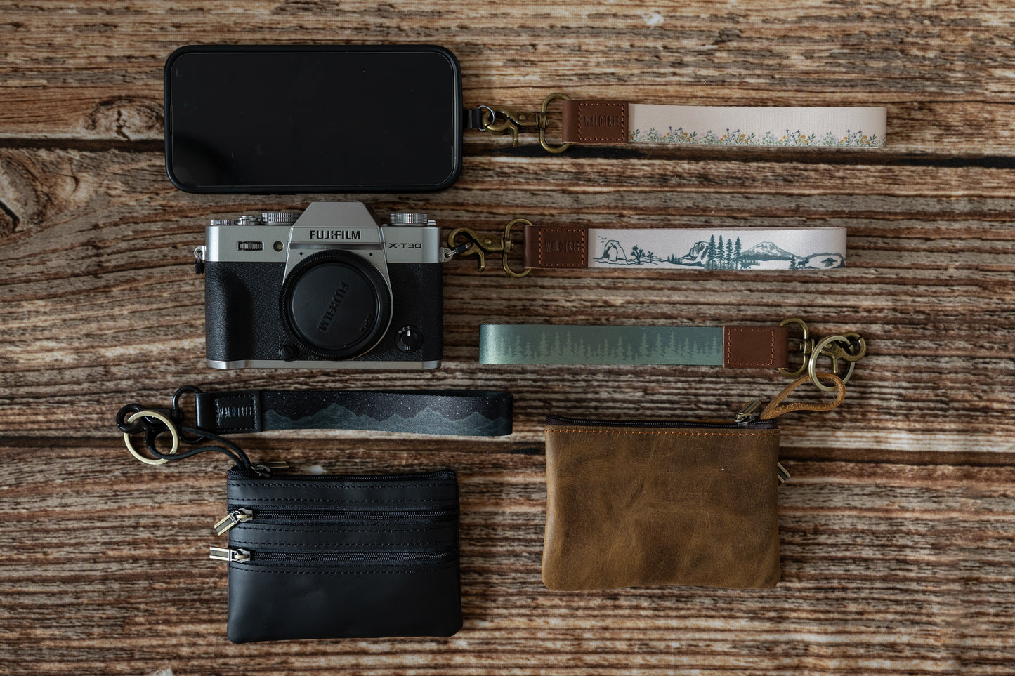 Assortment of personal items with wildtree keychains attached. personal items are phone, camera, wallet