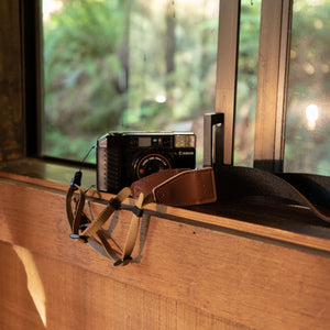 Black and Brown Wildtree Crossbody Camera Strap sitting on window