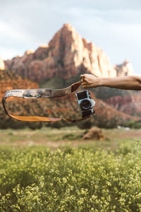 extended arm holding Wildtree national park camera strap in zion national park
