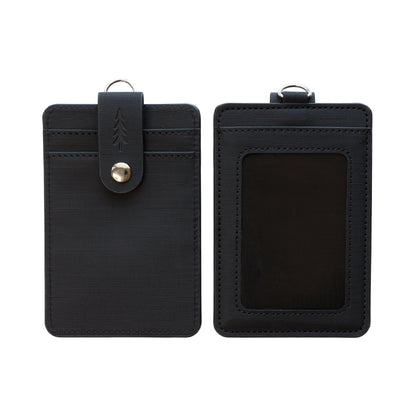 A clean, overhead studio photograph showing the front and back of the dark textured ID badge holder positioned side-by-side against a plain, bright white background. The fine grid texture of the material, the stitching details, and the embossed pine tree on the snap closure strap are clearly visible.