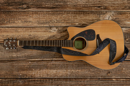 Black midnight mountain guitar strap featuring mountain range and stars. Attached to guitar lying on wood floor