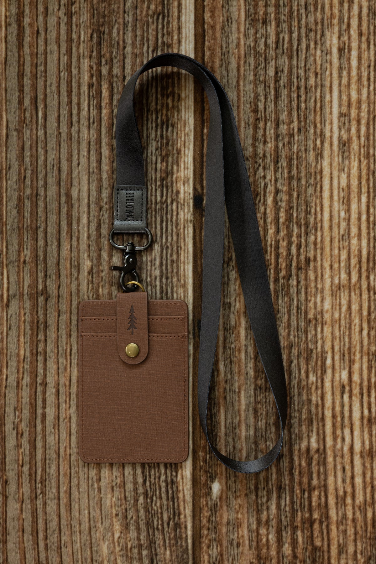 Black Neck Lanyard attached to a brown vegan leather cardholder embossed with a pine tree design