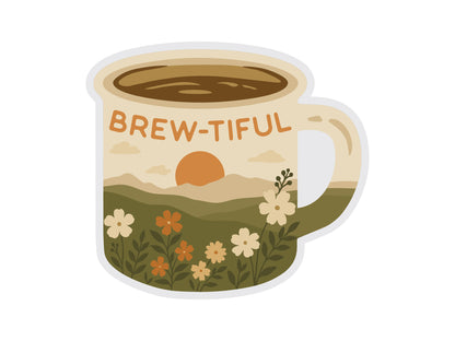 A high-resolution digital graphic of a die-cut vinyl sticker. The sticker is shaped like a cream-colored campfire mug with the pun "BREW-TIFUL" written in orange text. The body of the mug features an illustrated landscape of a soft orange sun setting over rolling hills, with a foreground of white and orange wildflowers and green foliage.