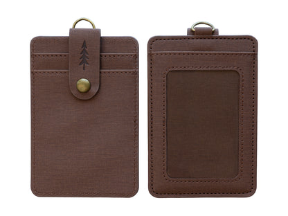 A product shot isolated on a solid white background showing the front and back of a brown textured ID badge holder side-by-side. The left side shows the front view with card slots and a snap-button closure strap embossed with a pine tree. The right side shows the back view with a clear ID window and top loop.