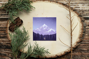sticker of a small cabin in the woods below a mountain and surrounded by tress