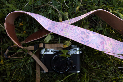 focusing on the close-up texture of the vibrant pink botanical wildflower printed fabric loop alongside a rustic pinecone on the lawn.