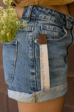 Load image into Gallery viewer, Floral flower field wristlet keychain hanging our of shorts pocket
