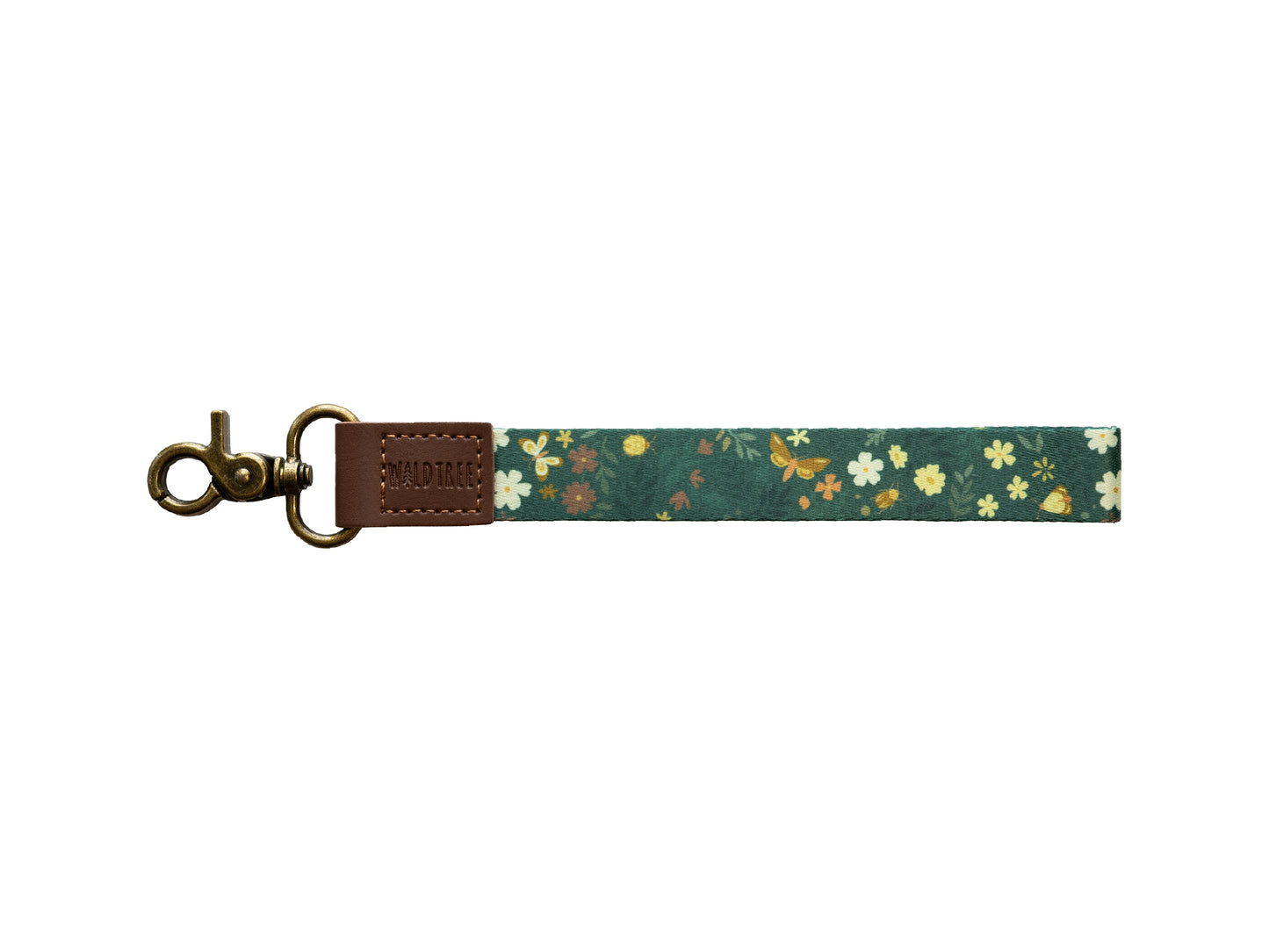 Flat lay of the Flutter & Fern wristlet keychain on a white background, showing the dark green strap printed with white daisies, small brown and yellow flowers, and gold butterflies, a brown vegan-leather tab embossed with the WILDTREE logo, and a bronze swivel clasp.