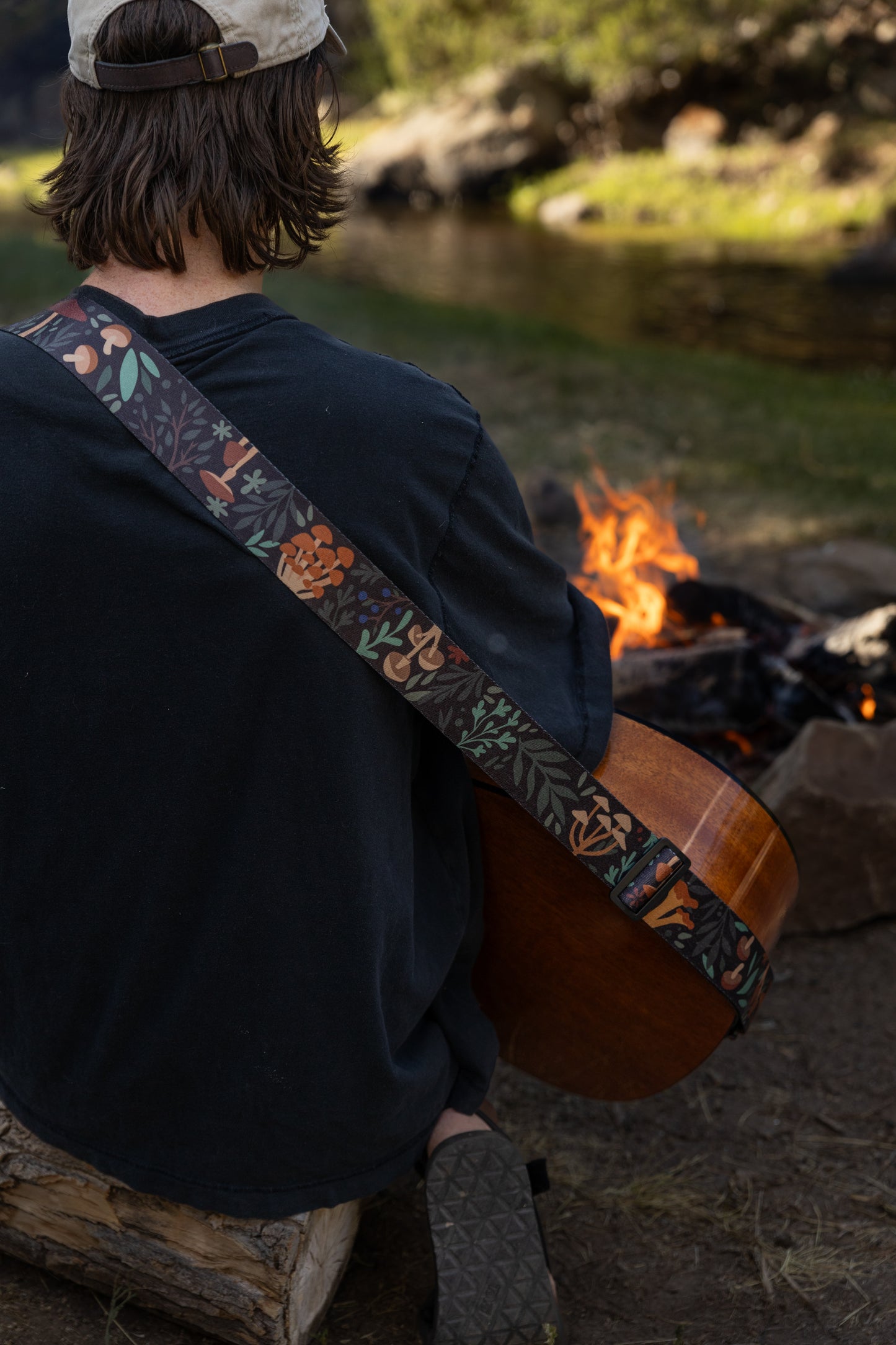 Forest Foliage guitar strap outside around a campfire playing guitar