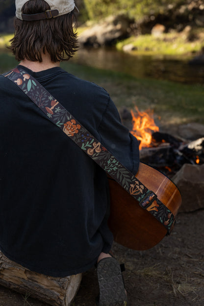 Forest Foliage guitar strap outside around a campfire playing guitar