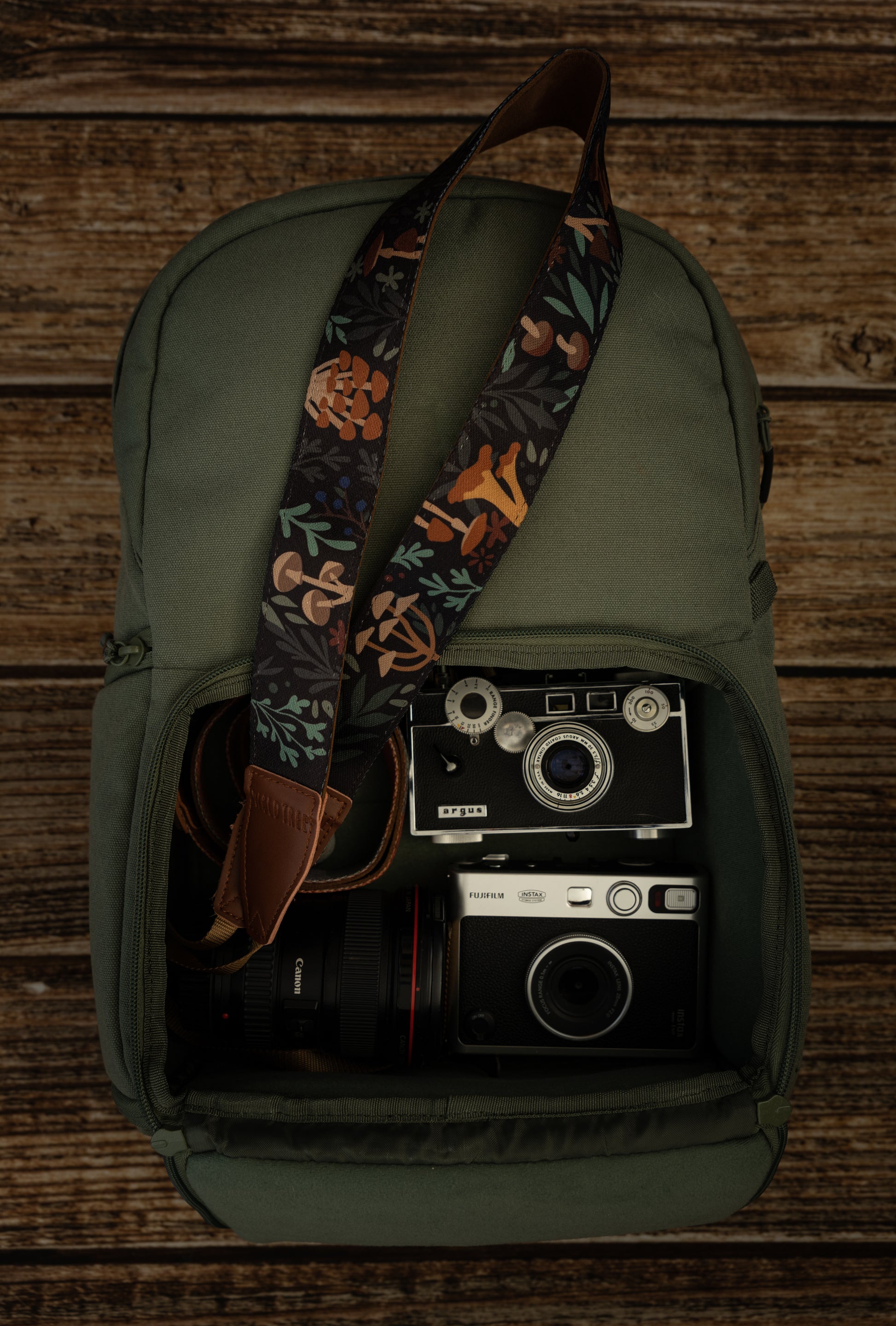 Wildtree Forest Foliage Camera laying out on green brevite backpack - Best camera strap for canon camera.