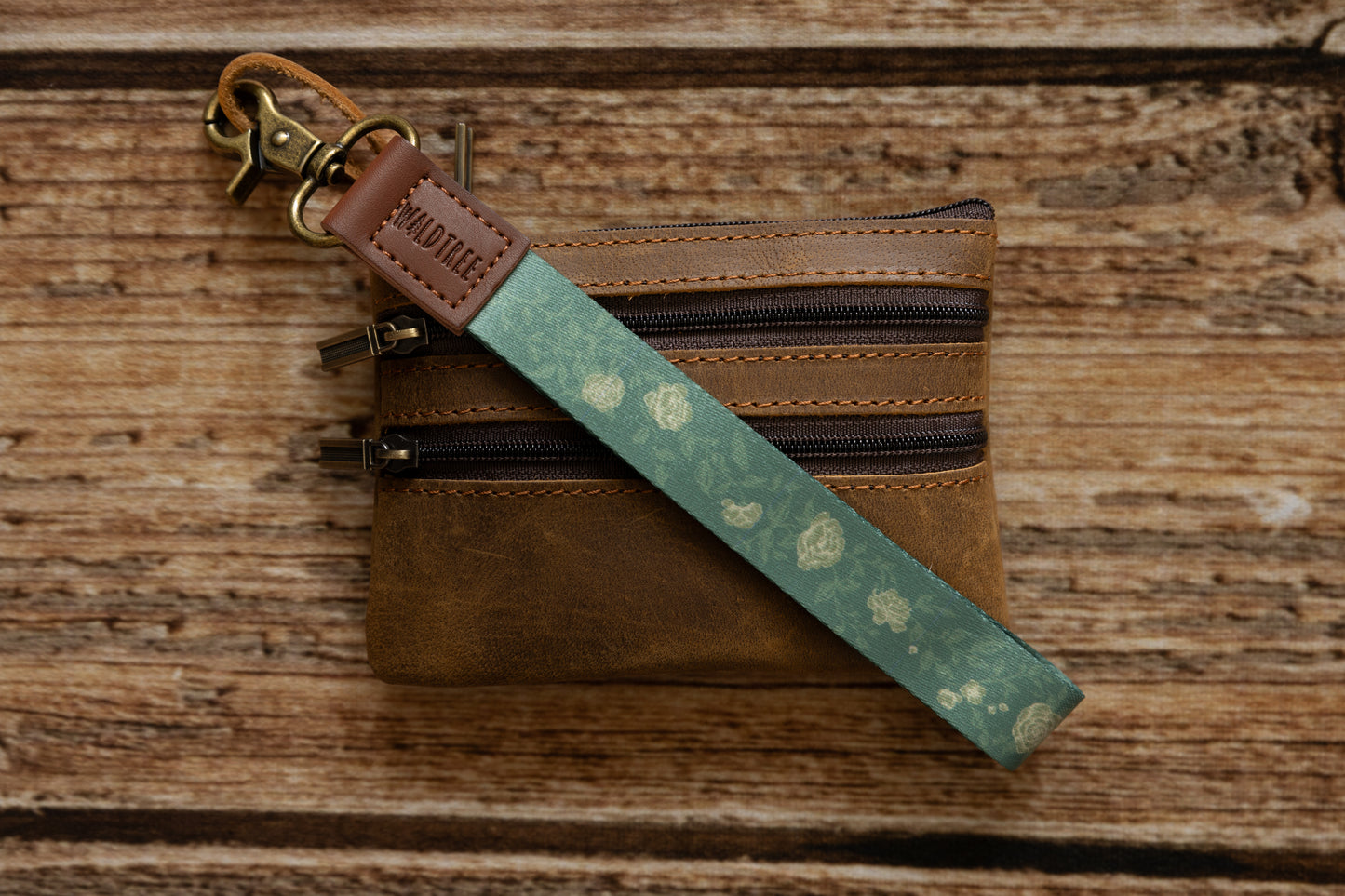 Green Wristlet keychain printed with green vines and yellow flowers connected to brown coin wallet