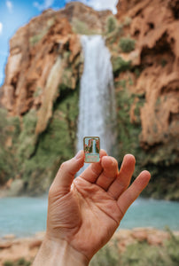 Havasu falls pin being held out in front of havasu fall havasupai indian reservation in the grand canyon
