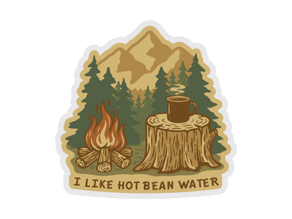 A digital graphic of a die-cut vinyl sticker featuring a cozy campfire scene. The illustration shows a roaring campfire next to a steaming brown coffee mug resting on a tree stump, with a background of dense evergreen trees and golden mountain peaks. The text at the bottom reads "I LIKE HOT BEAN WATER" in a rugged, dark brown font, all framed by a thin white border against a white background.