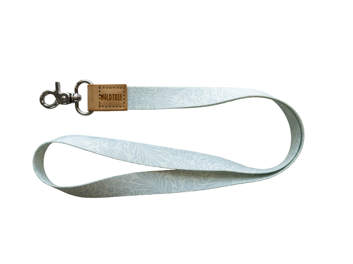 Flat lay of the Meadow Mist neck lanyard on a white background, showing the full pale sage-gray strap printed with a soft white fern leaf pattern, a tan vegan-leather tab embossed with the WILDTREE logo, and a silver swivel clasp.