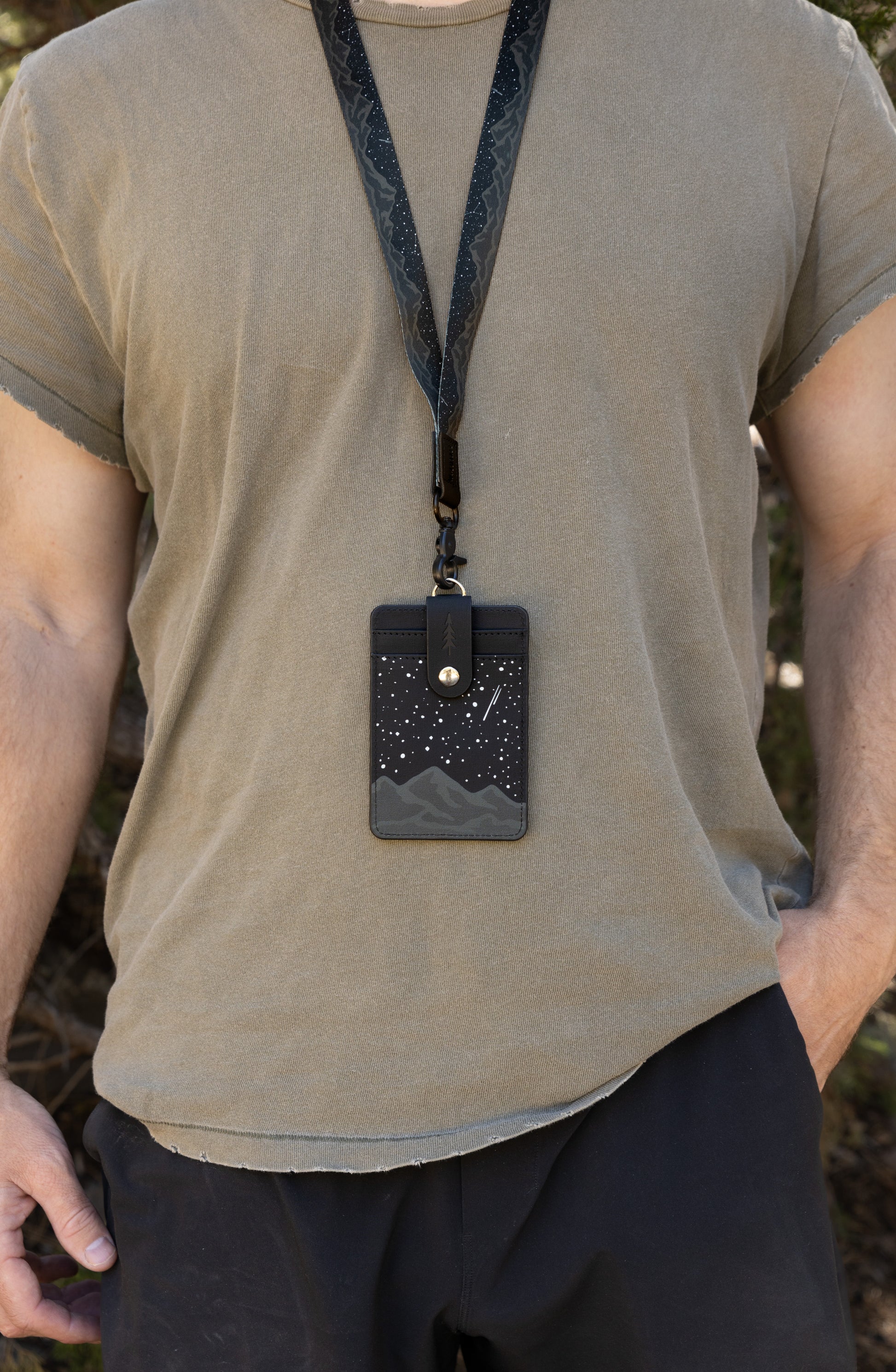 A tight close-up shot focusing on the front of the Midnight Mountain vertical card holder, highlighting the large clear plastic viewing window and meticulous white stitching. The clean black and white starry sky landscape design surrounds the badge sleeve, creating a professional look for school or work access cards.