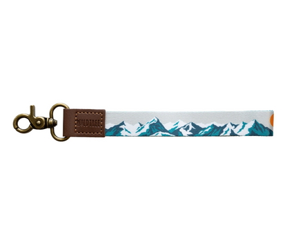 Flat lay of the Mountain Horizon wristlet keychain on a white background, showing the soft gray strap printed with a layered navy and teal mountain range silhouette.