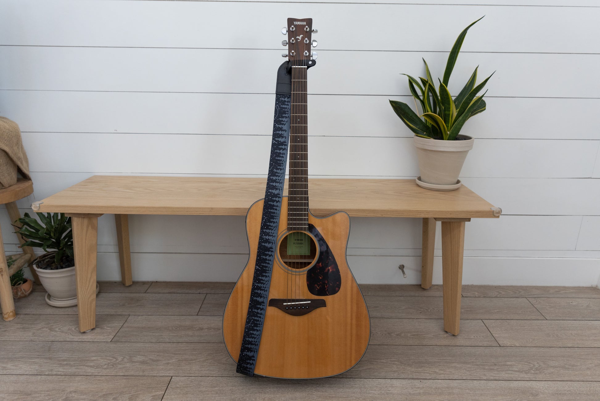 Black guitar strap with trees and stars attached to acoustic guitar