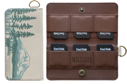 A studio product shot against a white background showing the closed front of the mountain-themed SD card holder next to the open interior containing six SanDisk memory cards.