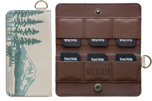 A studio product shot against a white background showing the closed front of the mountain-themed SD card holder next to the open interior containing six SanDisk memory cards.
