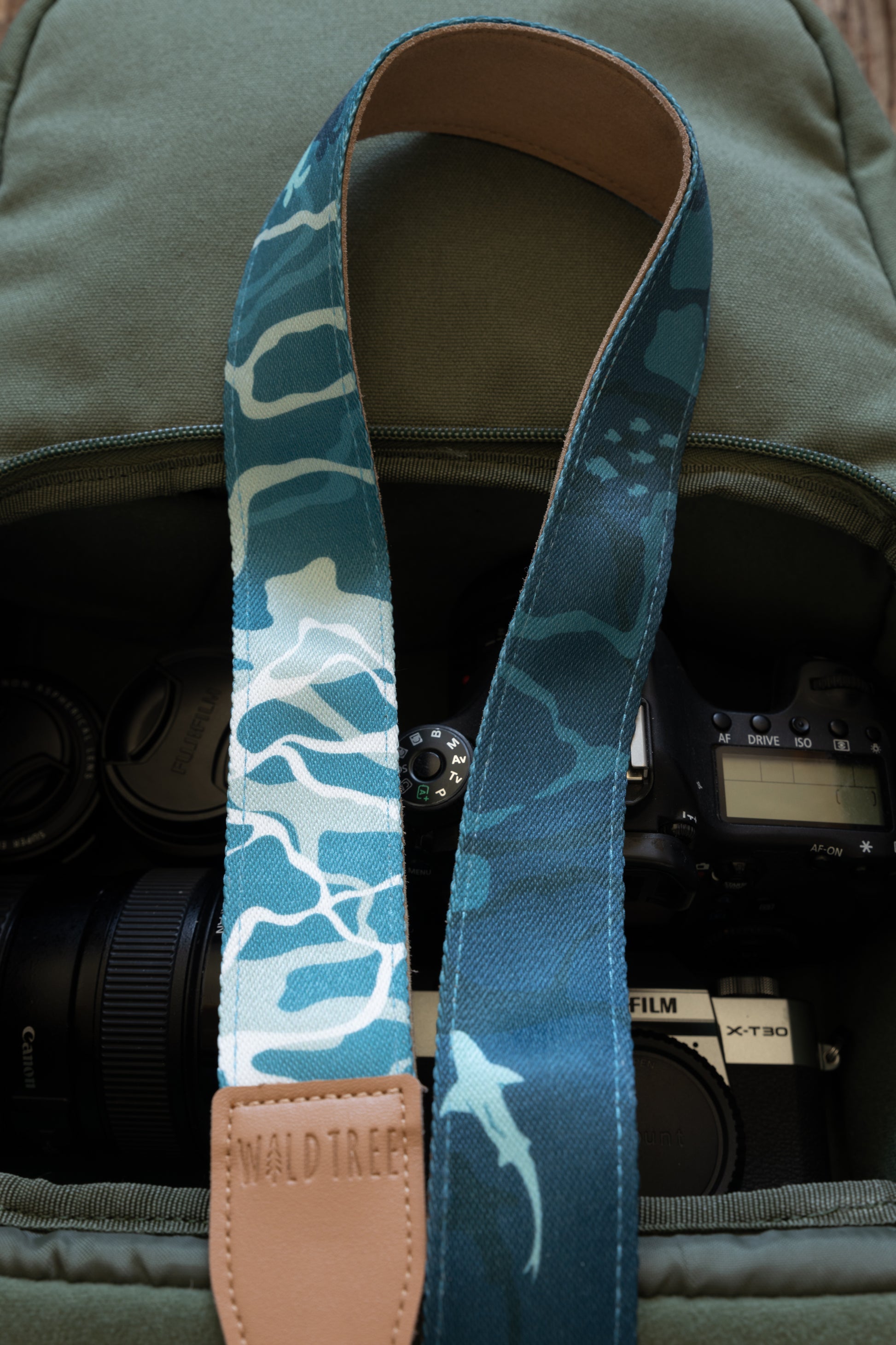 close up of ocean designed themed Camera Strap. mix of light and dark blues. Ocean water, turtles, sharks, fish and manta rays. light tan leather ends and light tan faux suede backing