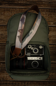 National parks camera strap in color laying out on green brevite back pack. 