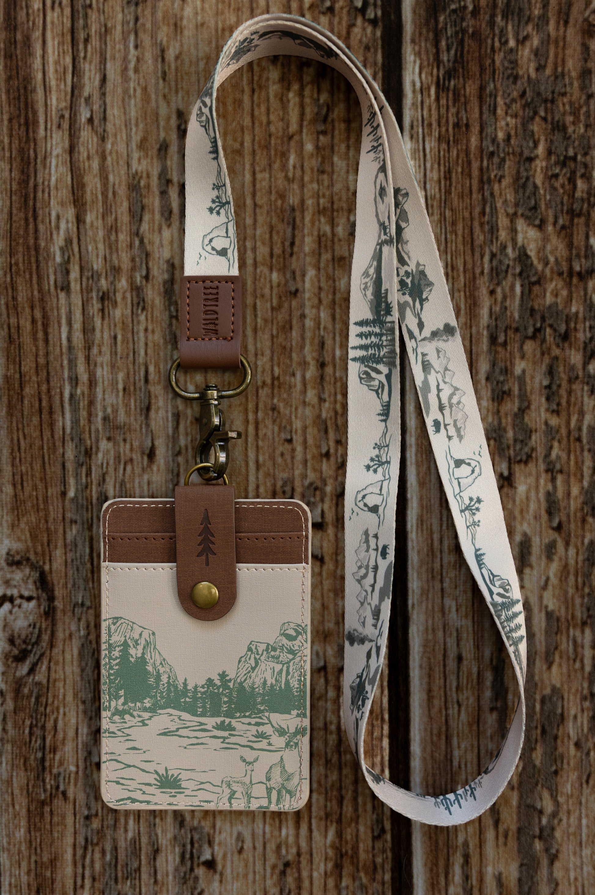 A tight close-up shot focusing on the back of the cream Yosemite ID holder attached to a matching lanyard. It showcases the brown vegan leather strap with a stamped tree icon snapped securely over the double card slots.
