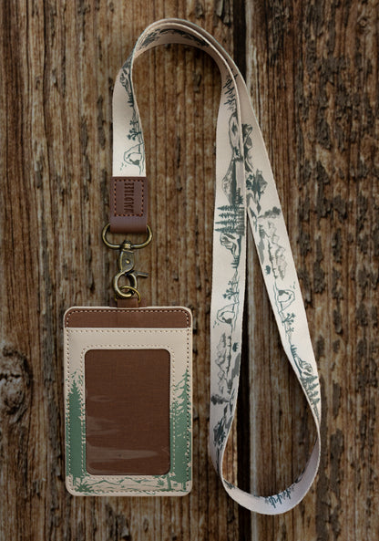A close-up lifestyle shot showcasing the back details of the Yosemite card wallet while being worn on a lanyard. It highlights the premium texture of the cream synthetic leather and the secure brown button strap overlaying the card slots.