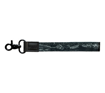 Flat lay of the Parks at Night wristlet keychain on a white background, showing the black strap printed with a night sky scene featuring mountain range silhouettes.