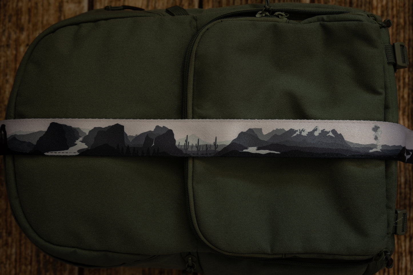 National parks camera strap in black and white laying out on green brevite back pack.