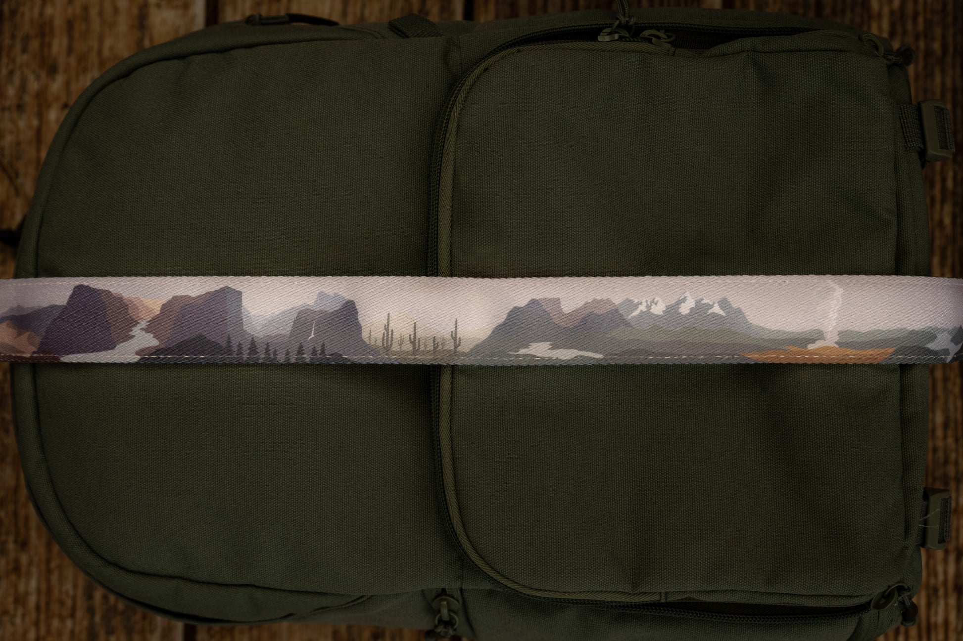 National parks camera strap in color laying out on green brevite back pack. - Best camera strap for Canon cameras and all other makes and models.