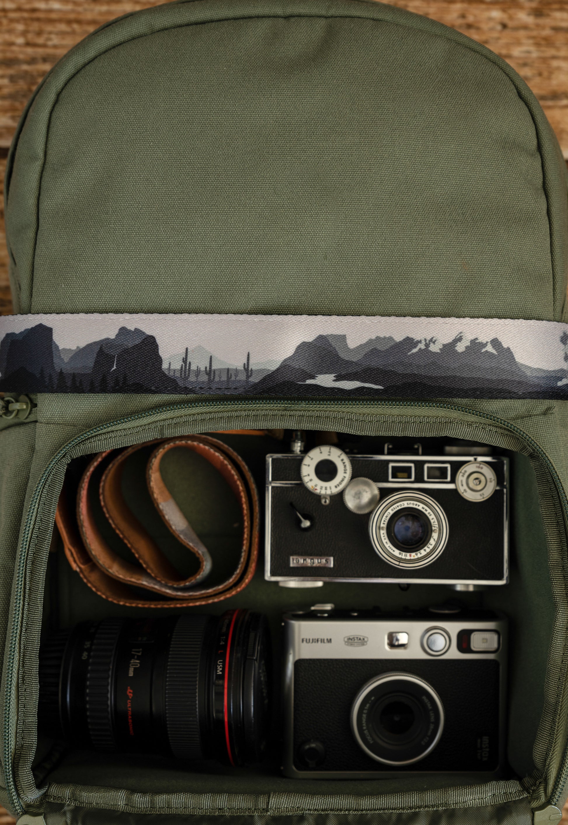 National parks camera strap in black and white laying out on green brevite back pack.
