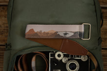 Load image into Gallery viewer, Wildtree national parks in color wrist strap laying across green Brevite backpack 
