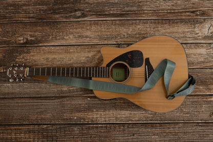 Pinetree printed guitar strap attached to acoustic guitar lying on wood floor