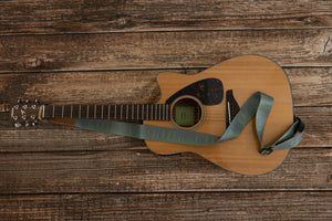 Pinetree printed guitar strap attached to acoustic guitar lying on wood floor