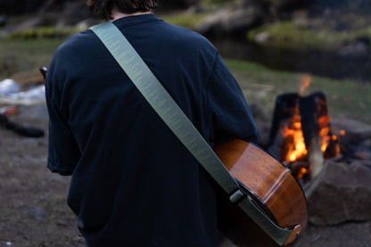 Pine tree guitar strap outside around a campfire playing guitar