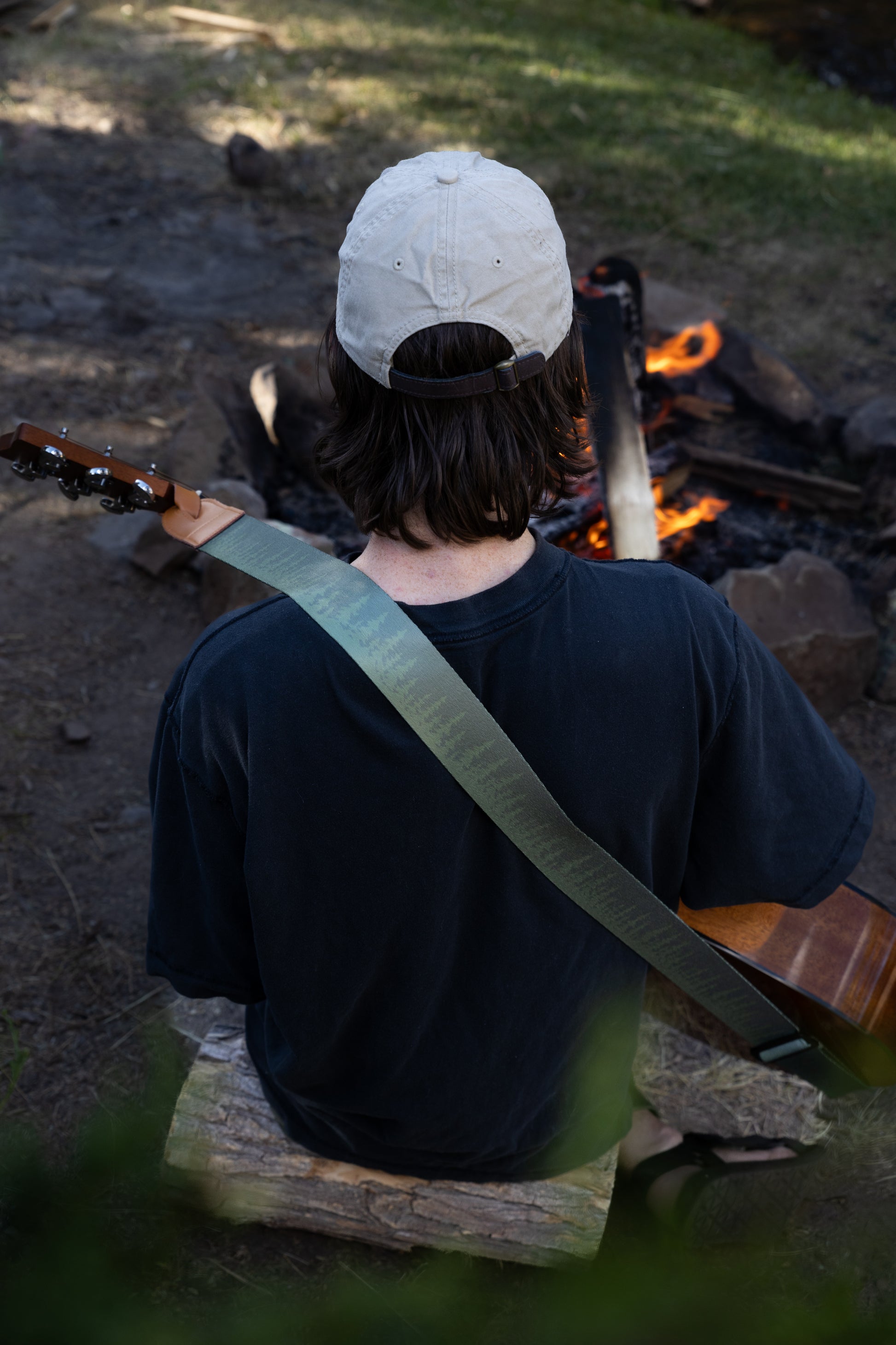 Pine tree guitar strap outside around a campfire playing guitar