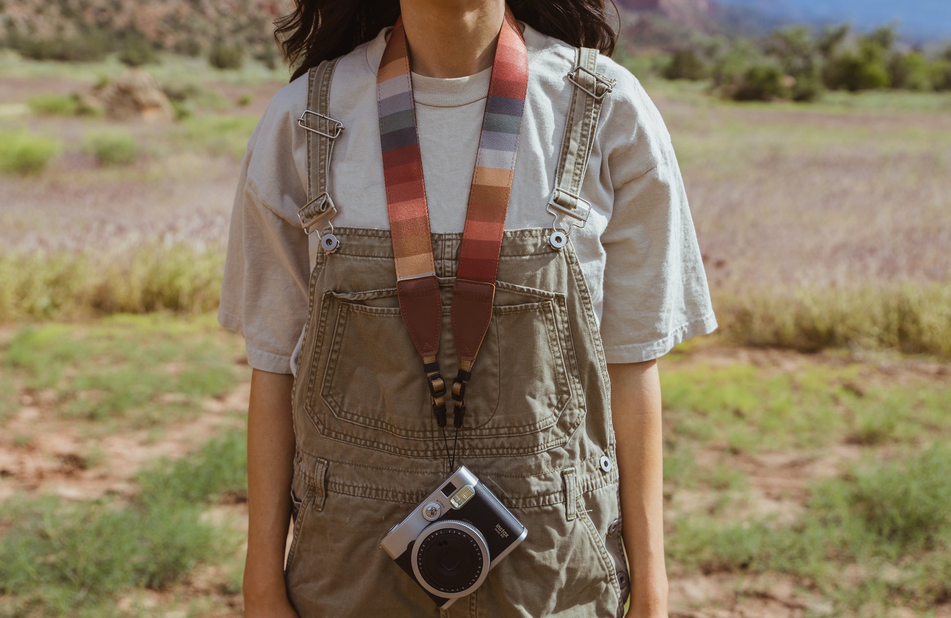 Retro striped camera strap hanging from women's neck holding film camera