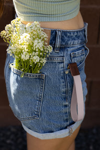 Women with flowers in back pocket and pink rose cloud wristlet keychain hanging out of front pocket