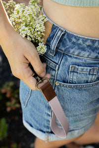 Women with flowers in back pocket holding pink rose cloud wristlet keychain hanging out of front pocket