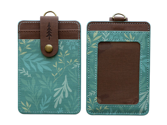 A studio product shot showing both the front and back of the green botanical ID holder isolated on a white background. It provides a clean, clear view of the clear ID window, back card slots, and pine tree snap closure.