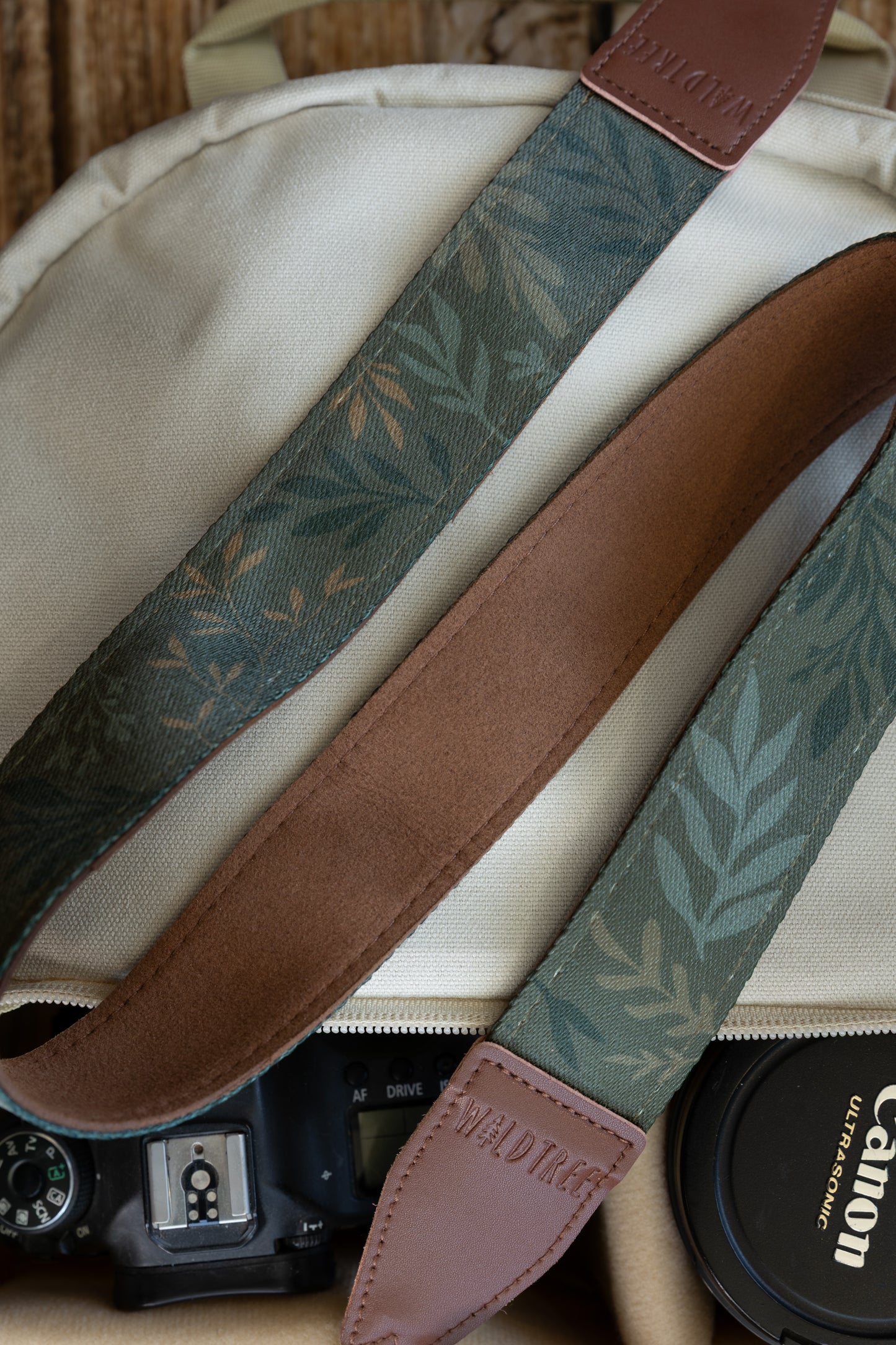 Close-up detail shot of the WILDTREE "Silent Grove" camera strap, highlighting the floral green printed fabric and brown vegan leather ends.