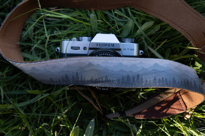 Silent Summit camera strap detailed horizontal shot emphasizing the dense pine tree and layered mountain silhouette graphic print transitioning from deep blue to misty gray.