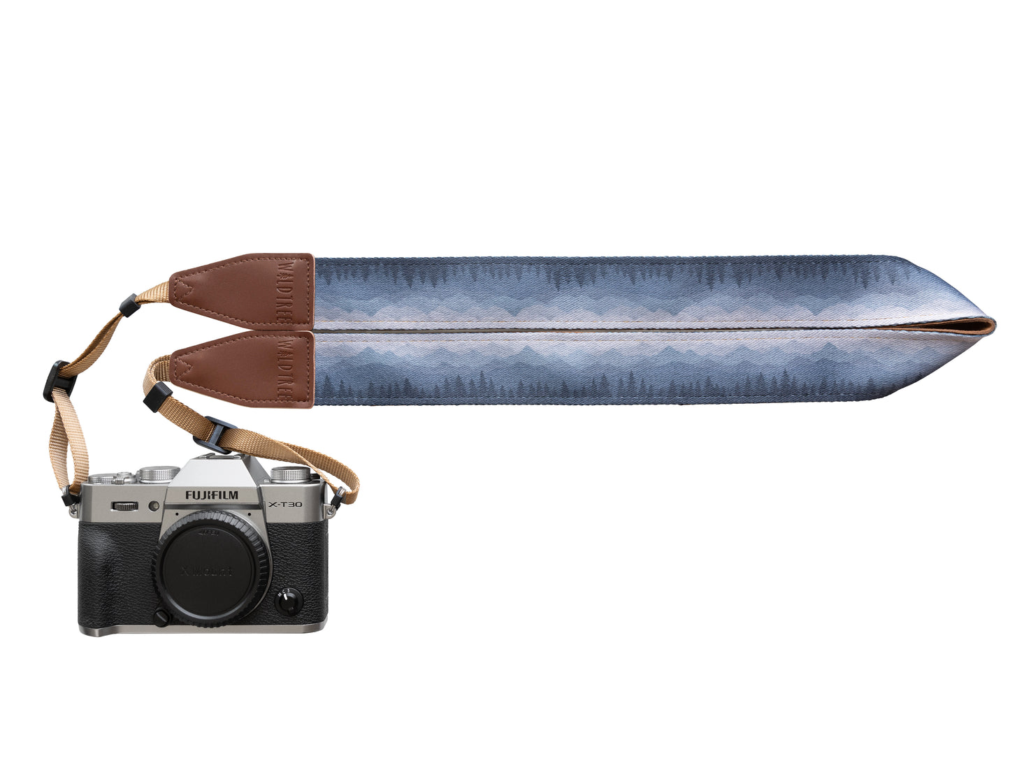 Silent Summit camera strap studio product design shot showing the folded fabric band with a blue-to-gray pine forest gradient illustration and stitched brown leather tips attached to a silver mirrorless camera.