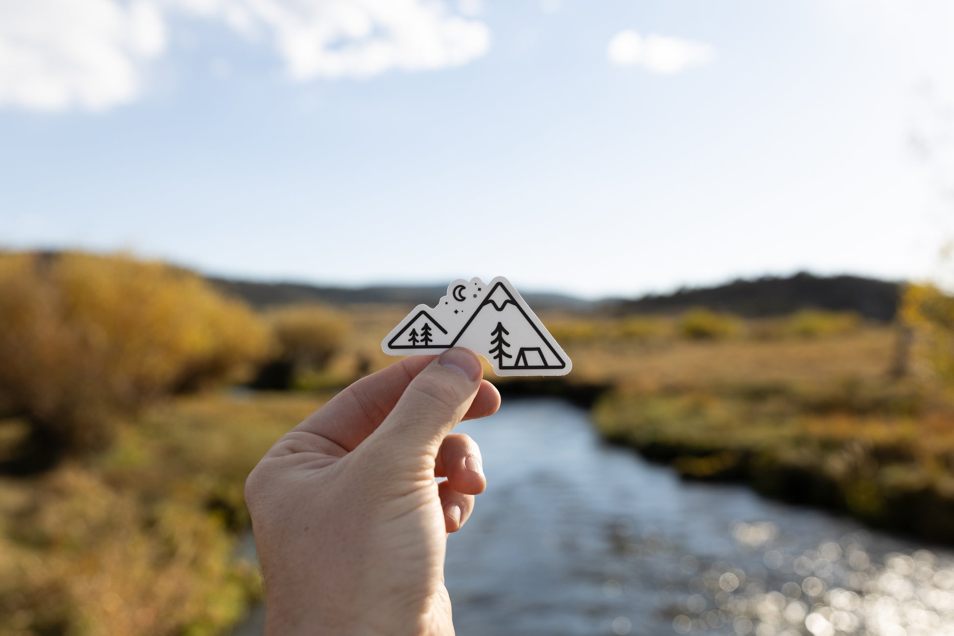 Simplistic line art of mountains, trees, moon and tent as a sticker