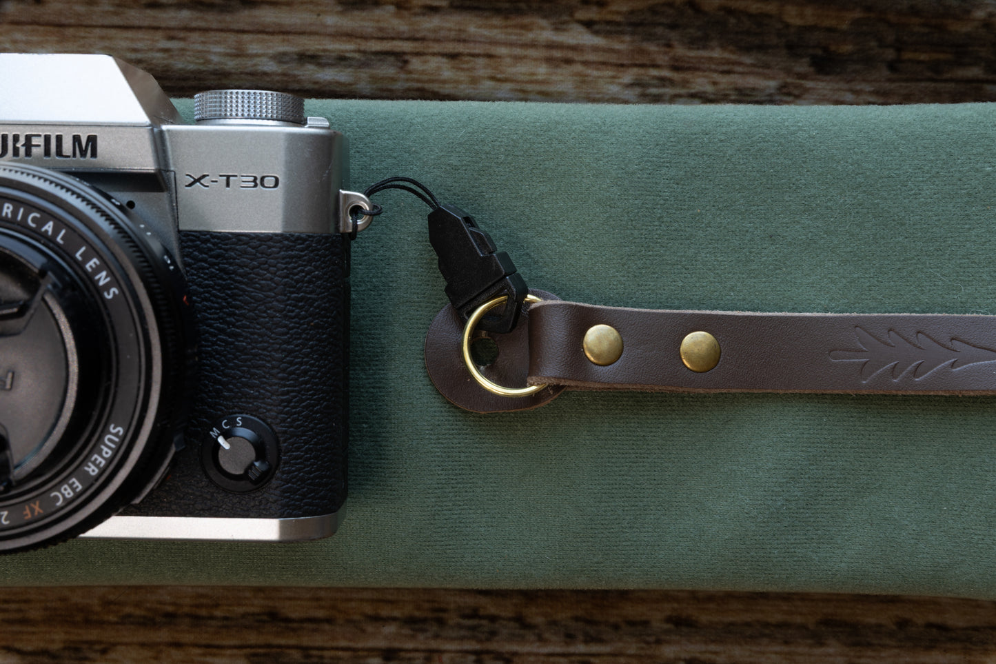 lose-up detail showing the included black quick release buckle adapter attached to the vintage leather camera strap's bronze O-ring and O-ring leather guard.