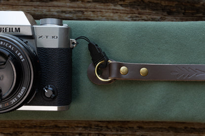 lose-up detail showing the included black quick release buckle adapter attached to the vintage leather camera strap's bronze O-ring and O-ring leather guard.