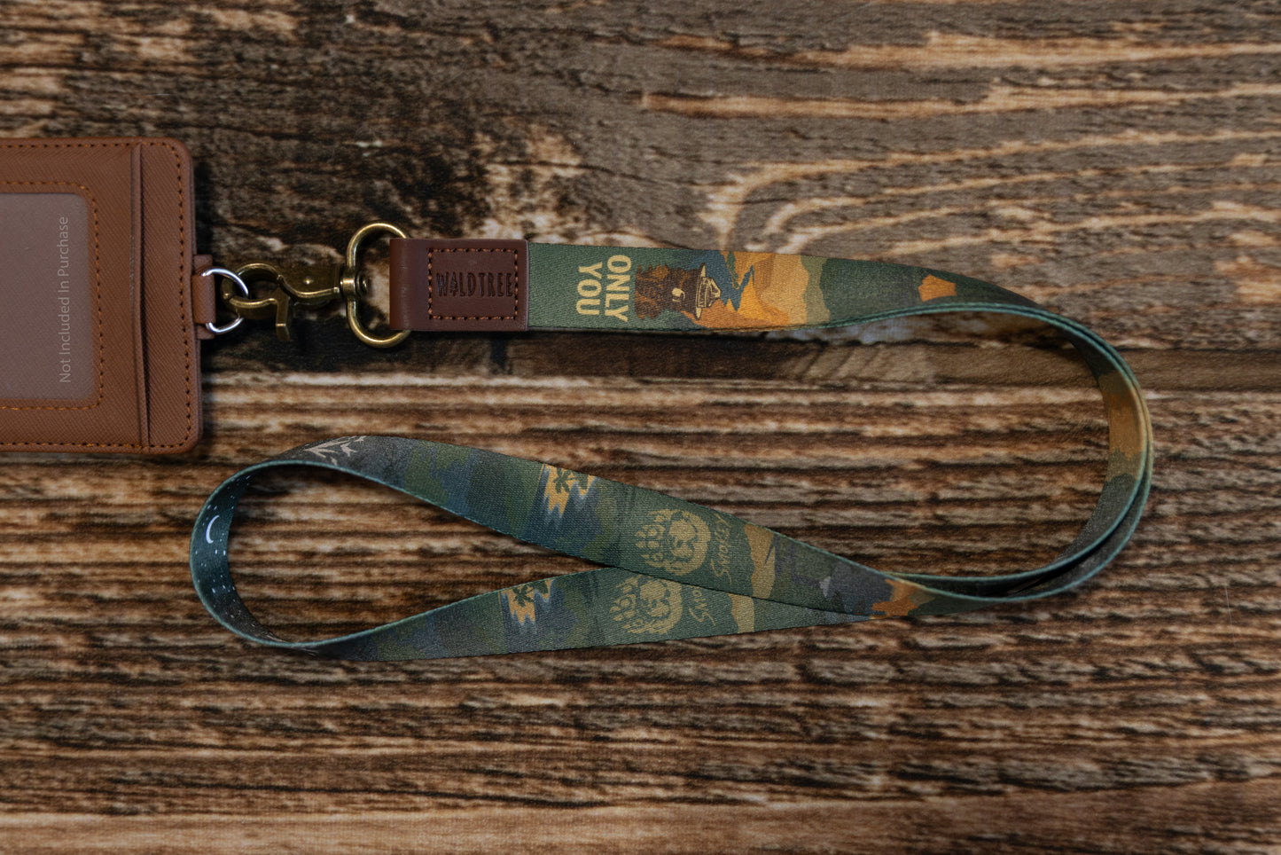 The Smokey Bear lanyard attached to a brown faux-leather ID badge holder (not included) on a rustic wood surface, showing its functionality for work or school.