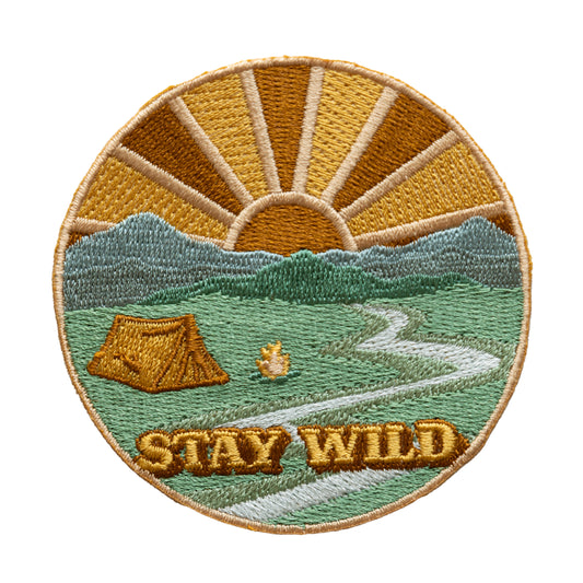 Stay wild patch. Design featuring tent, sun and sun rays, mountains, river, camp fire with the words "Stay Wild"